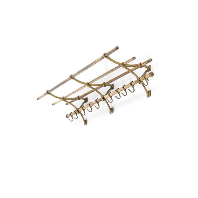 An oversized brass art deco style coat and luggage rack with a sturdy arrangement of three luggage bars with a rack...