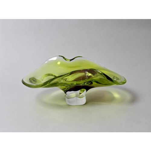 An impressive Murano art glass bowl distinguished by its luminous apple-green coloration, warm brown accent, and flowing...