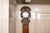 An antique French provincial tall oak longcase clock with warm oak tone, richly carved crest of foliage, flowers and a...