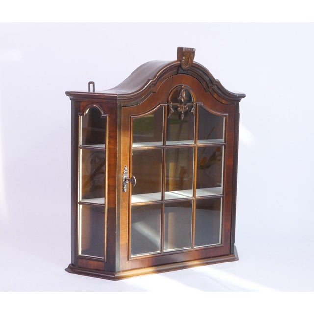 Vintage wooden display with glass door and shelves in the inside. It has a beautiful ornament on the top and front door...