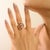 This elegant Art Deco-inspired cocktail ring is crafted in solid 14K yellow gold, showcasing three oval-cut rubies with a...