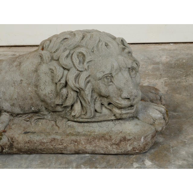 A pair of English cast stone reclining lions statues from the early 20th century, on rectangular bases. Created in England...