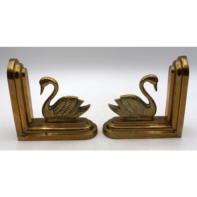 Pair of mid century modern brass swan bookends, Continental. The swans well modeled and cast swimming along the bookends,...