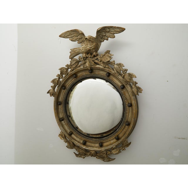 An English silver gilt convex girandole bullseye mirror from the early 20th century, with eagle motif. Created in England...