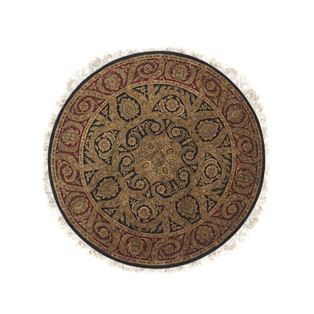 A hand-knotted wool rug, made in India and measuring 8' x 8'. Floral drawing carried across the field inside a traditional...