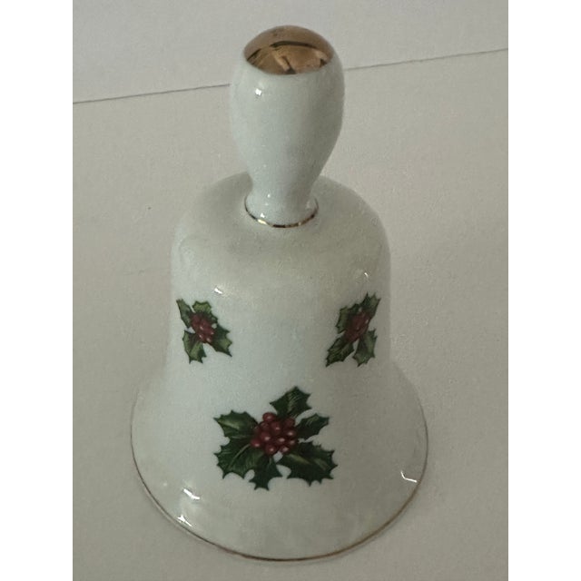 Vintage white bone china bell. The body is adorned with hand painted green holly leave and red berries. Accented with gold...
