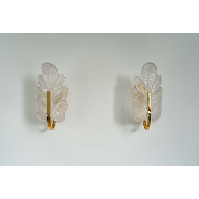 Pair of Mid-Century Hollywood Regency Murano glass leaf wall sconces in thick, clear graniglia glass and polished brass,...