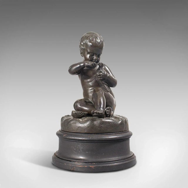 This is an antique putto statue. A French, bronze seated cherub figure with small bird in hand, dating to the late 19th...