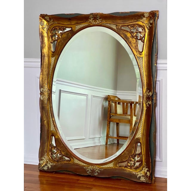 Large Italian baroque giltwood and paint decorated oval beveled mirror in a rectangular frame, Italy, circa 1920....