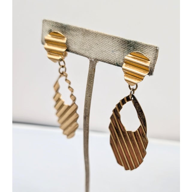 1989 goldtone "corrugated" round top with an oval cut-out drop clip earrings. Marked "NAPIER©" on the clips. Measure: 3...