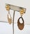 1989 goldtone "corrugated" round top with an oval cut-out drop clip earrings. Marked "NAPIER©" on the clips. Measure: 3...