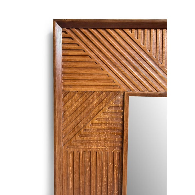 Richly toned wood statement mirror showcasing a geometric carved pattern with linear details. Its Generously sized square...