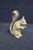 Folk art wooden squirrel figure with a curled tail and hand-painted details in muted yellow, brown, and cream tones....