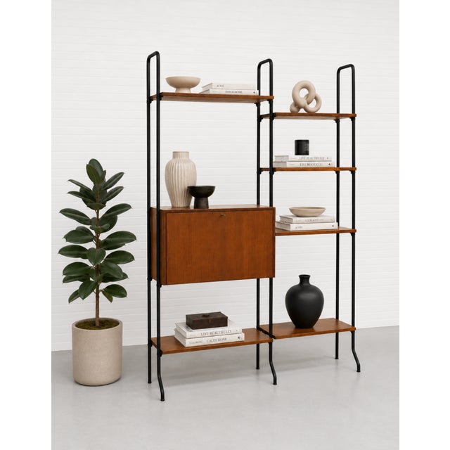 Vintage Mid Century Modern Italian wall unit featuring warm teak and a sleek black metal frame. This architectural piece...