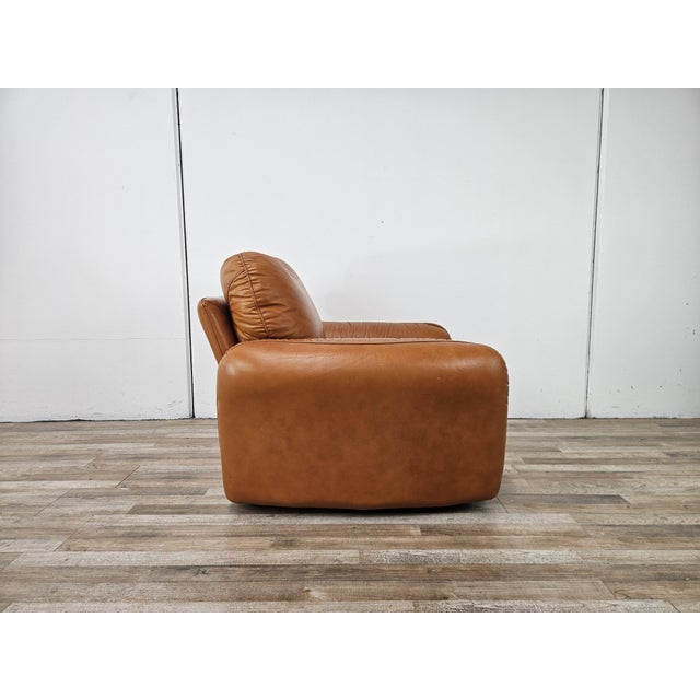 1970s orange leather armchair, Piumotto model designed by Arrigo Arrigoni for Busnelli. The armchair, with its modern and...
