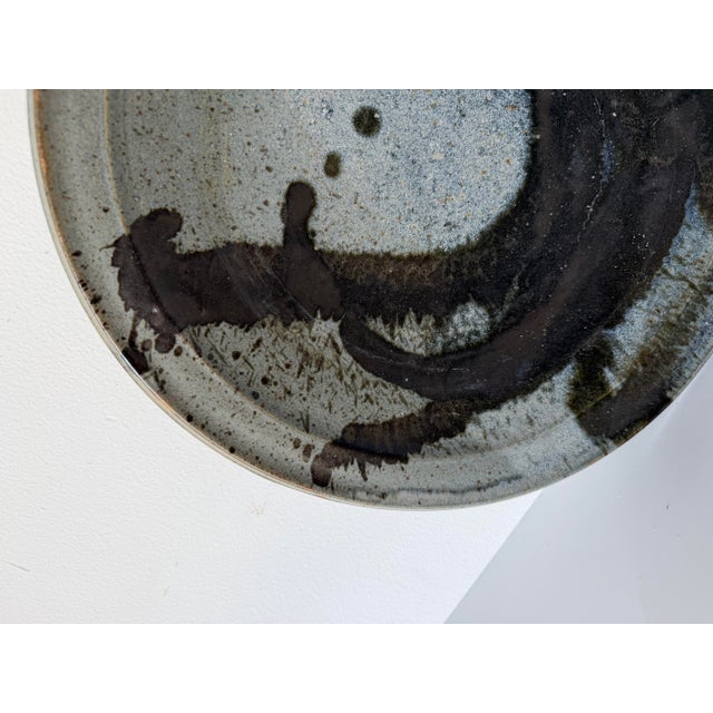 Striking 1980s studio pottery charger featuring a beautifully hand-glazed abstract design in soft gray, blue, and charcoal...