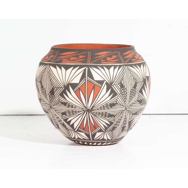 An Acoma Pueblo pottery vase by the Native American ceramicist Corrine Chino. This vase features a rounded shape with an...