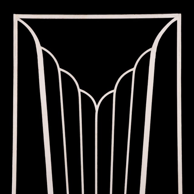 A pair of striking Art Deco iron door panels, each featuring a bold stylized fountain or fan motif of elongated, gently...