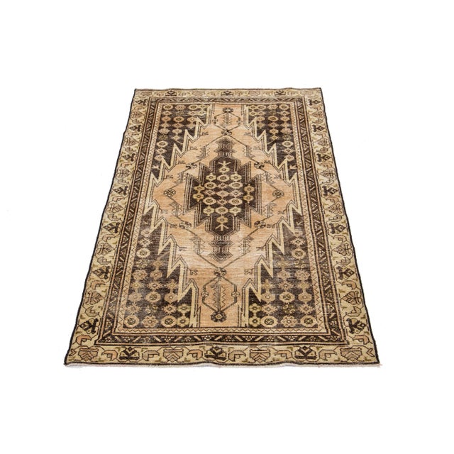 This vintage Persian Hand-knotted wool rug has a tan field with dark brown accents in an all-over medallion design. This...