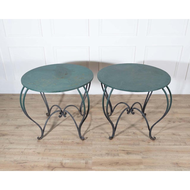 A beautiful pair of round iron tables, late 19th to early 20th century, featuring gracefully shaped legs and original...