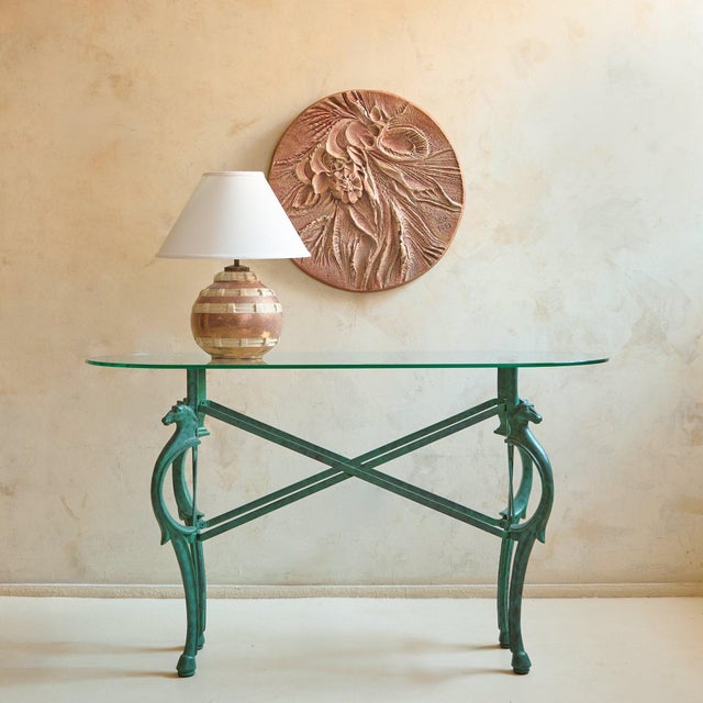 A French Neoclassical Revival iron console table from the 1980s. An elongated oval glass top appears to float lightly...