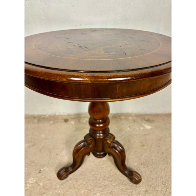Elegant round occasional table featuring a beautifully inlaid top and sculptural tripod base. The circular top displays...