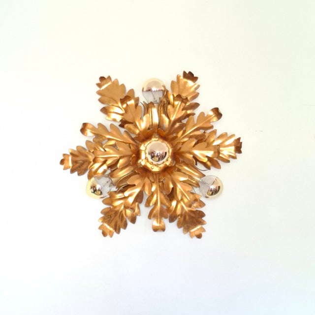 The light fixture is crafted from metal and features lush, stylized leaves arranged in a star shape. a magnificent ceiling...