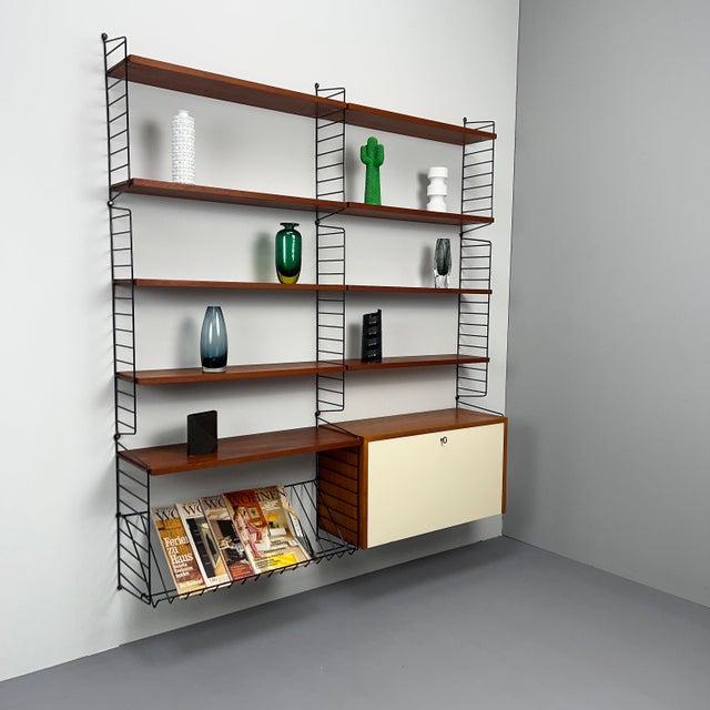 Beautiful shelving combination by String, design: Kajsa & Nisse Strinning in teak with a rare cabinet element featuring an...