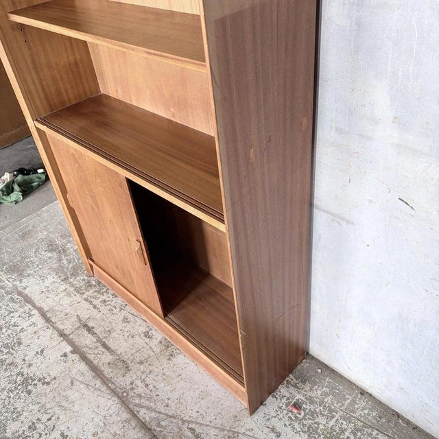 A beautifully proportioned mid-century teak sliding door bookcase by herbert gibbs, combining elegant british...