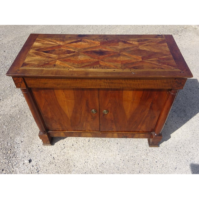A 19th-century buffet with two doors and one drawer, featuring a curved top. The magnificent marquetry top displays...