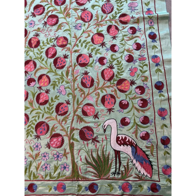 Hand-embroidered Suzani panel from Uzbekistan — a fruiting pomegranate tree in crimson and rose on a mint green silk...