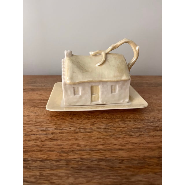 A beautiful Belleek covered butter dish depicting a rustic Irish cottage marked with the 7th Gold/Brown seal from 1980-1992.