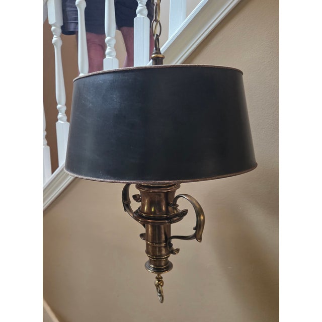 Vintage brass hanging chandelier. The shade is black with a metallic gold/black gimp cord at top and bottom. Inside the...