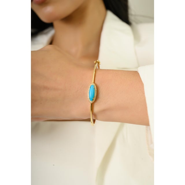 This elegant bangle bracelet showcasing one natural turquoise cabochon totaling 2.22 carats, set in 14k yellow gold. oval...