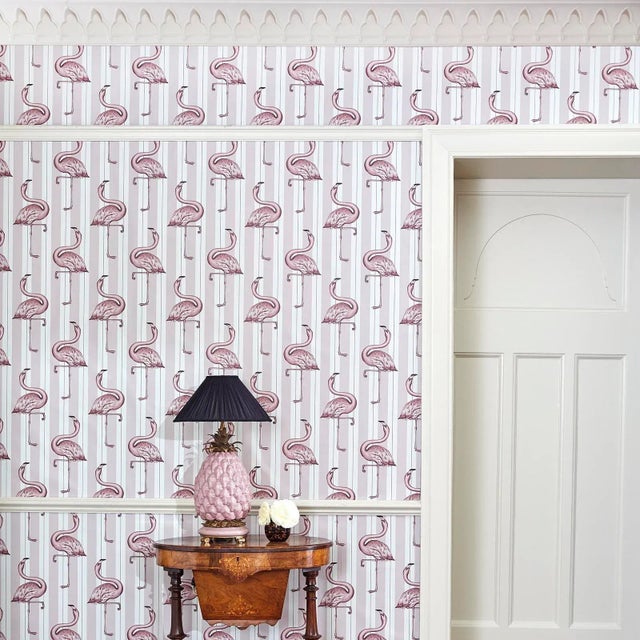 Witty and pretty in equal measure, the FLAMBOYANCE wallpaper layers flamingos over bold stripes in off-white and macaroon-...