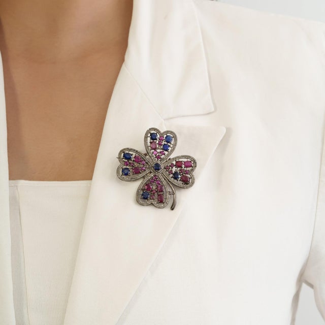 The Circa 1890s-Style 6.25 Ct Ruby & Kyanite Four-Leaf Clover Brooch Pendant is crafted in 925 sterling silver and...