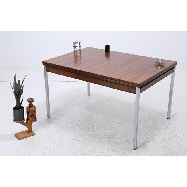 Vintage rosewood dining table from the 1960s with a clean, straight line and striking, dark grain. The extendable design...