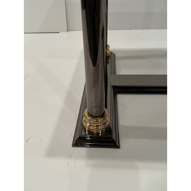 Stunning sleek cocktail table having a neoclassical aesthetic and stylish mix of black tinted steel columns with brass...