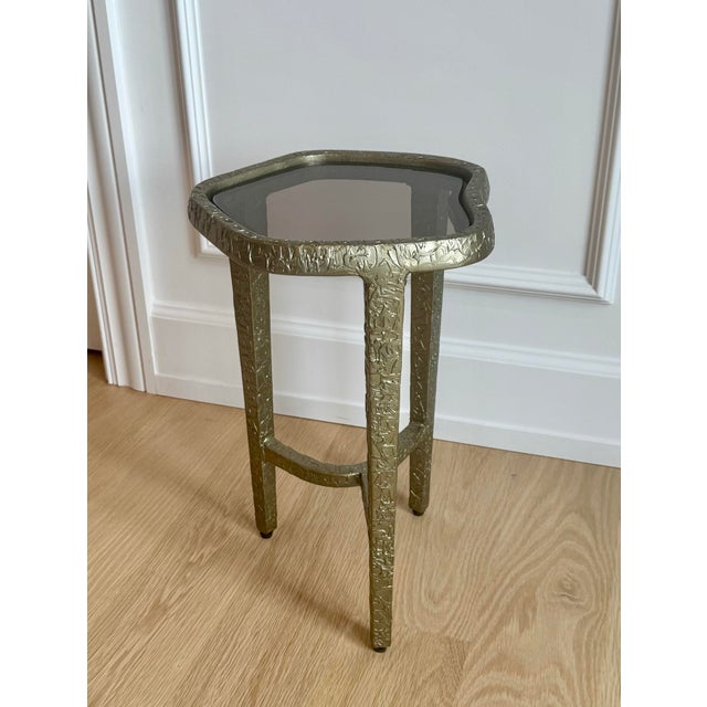 The Caracole Modern Edge "Contour" Side Table combines luxurious materials with an organic silhouette to create a...