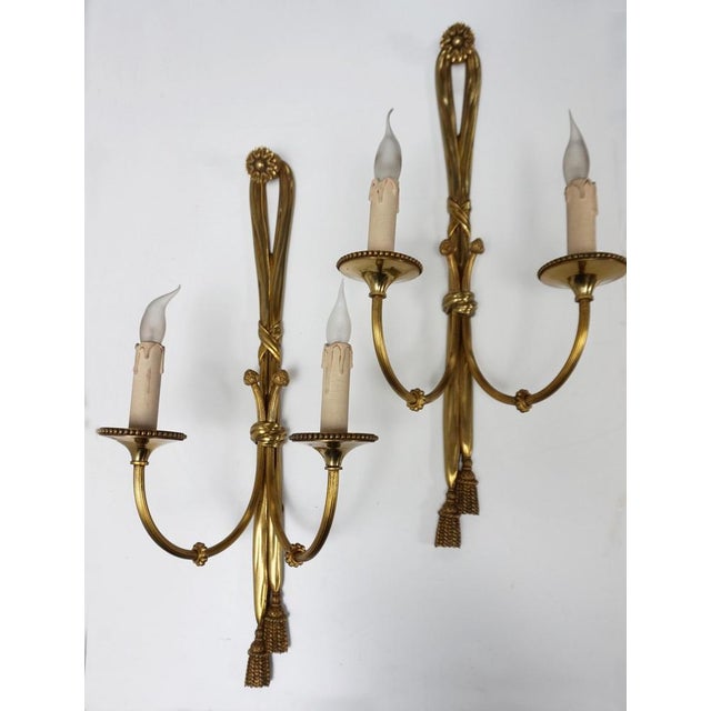Superb and large matching pair of cast gilt bronze sconces in the shape of knotted ribbons tied with tassels, each holding...