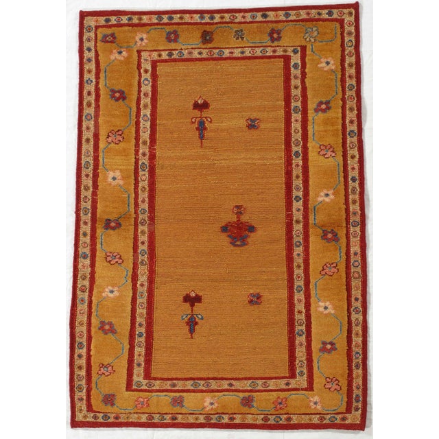 Vintage Persian hand-knotted Gabbeh wool rug featuring a warm golden field with small stylized tribal motifs. The...