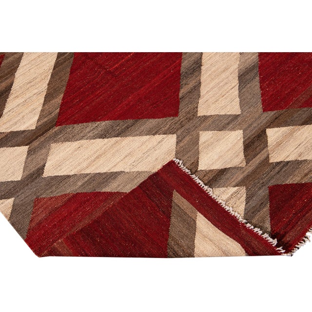 Beautiful modern Kilim flat-weave wool rug with a red field. This piece of art has beige and brown accents in a gorgeous...