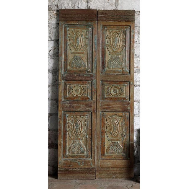 An exceptional pair of antique Indian carved wooden doors, featuring an elegant floral vase motif rendered in intricate...