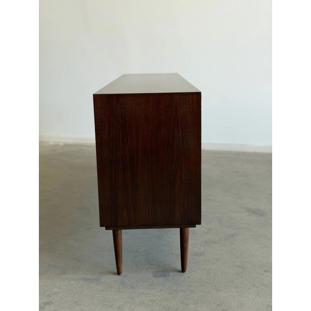 W71 D17 H32 The “Danish Modern Credenza” is crafted in teak wood and has been fully refinished in a deep, rich stain. This...