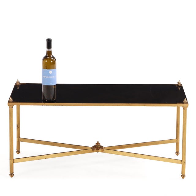 The table features an inset black mirrored top supported within a gilt brass frame . The design is restrained yet elegant,...