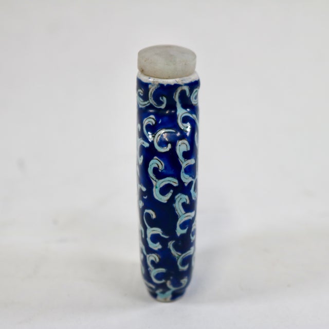 This antique Chinese snuff bottle showcases a charming blue and white enamel design with a lotus flower motif. This...