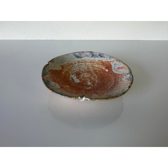 A captivating vintage studio pottery dish signed by Bom, showcasing an organic and earthy aesthetic with a richly textured...