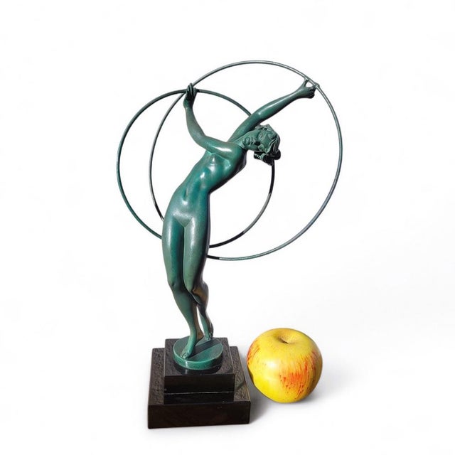 Spelter sculpture with a green patina depicting a nude dancer playing with two hoops, on a black marble base. Model named...