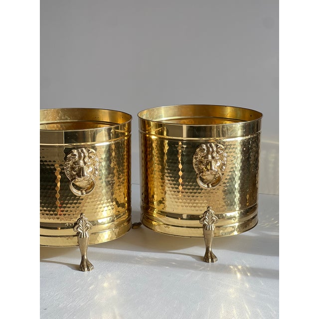This impressive pair of vintage brass lion head planters exemplifies the bold elegance of Hollywood Regency design....