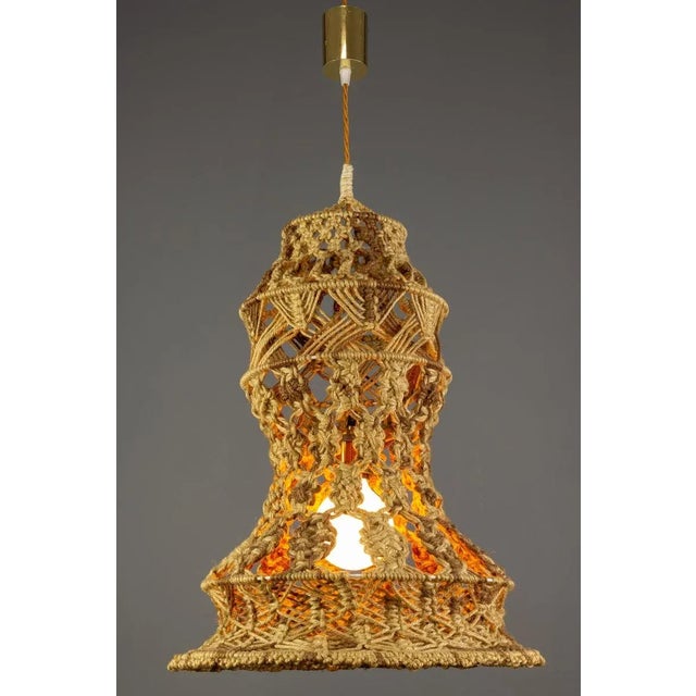 Beautiful pendant lamp with handmade braided macramé lampshade in warm and natural brown colors adorned with brown wood...
